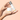 A model holding two skincare products from IMAGE Skincare Canada: a white jar of VITAL C hydrating repair creme and a white bottle of VITAL C hydrating anti-aging serum with a silver cap, set against a solid peach background.